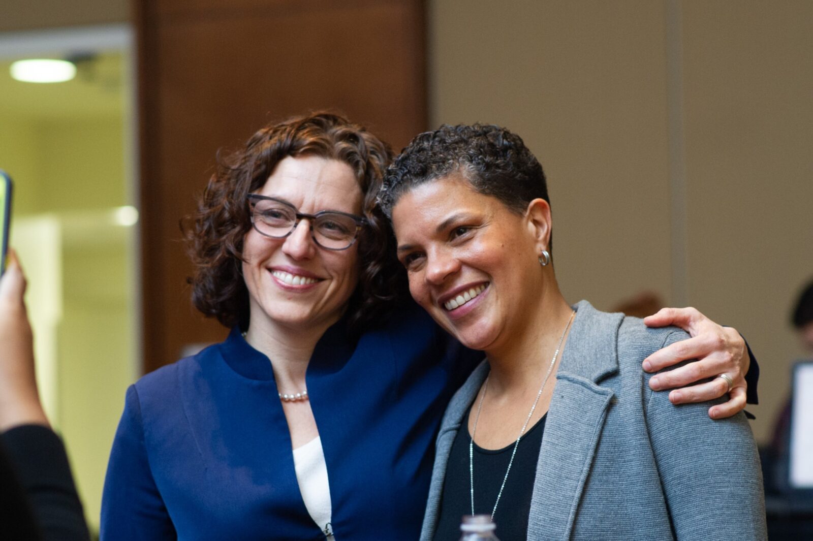 Pajarita Charles and Michelle Alexander smiling together indoors while posing for a photograph.